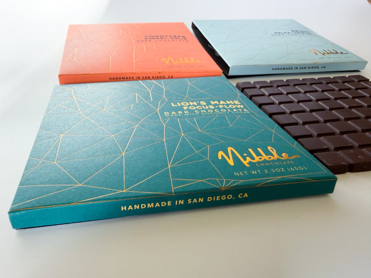 Flat lay of Nibble Reishi, Cordyceps and Lion’s Mane dark chocolate bars with handcrafted chocolate bar.