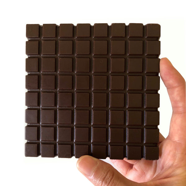Hand holding a square of dark chocolate featuring neat, small squares, highlighting its rich cocoa texture.